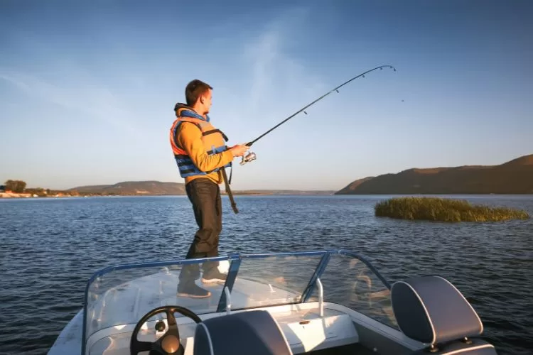 Young man wearing a life vest while fishing on a boat